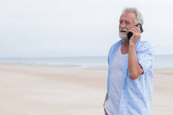 Старший одинокий мужчина говорит о вызове во время отдыха на море пляж чистое пространство для текста
 - Фото, изображение