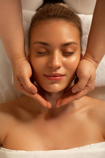 Appealing lady lying with closed eyes during relaxing massage - Valokuva, kuva