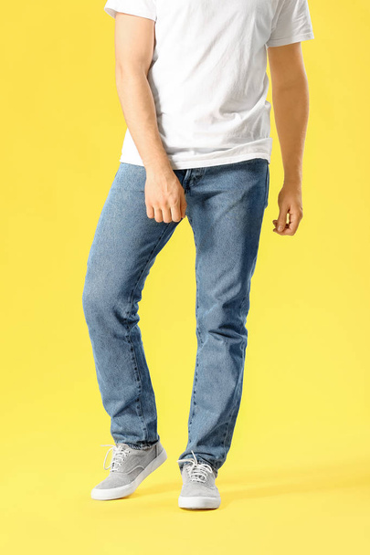 色の背景にジーンズのスタイリッシュな若者 - 写真・画像