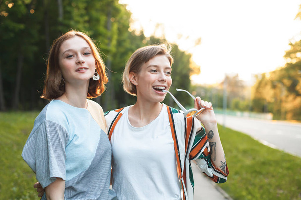 Дві веселі молоді жінки ходять у місті на заході сонця
 - Фото, зображення
