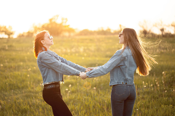 Two young women whirl outdoors in sunset - Foto, Imagen