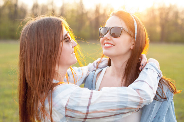 Two beautiful young women having fun on the field at sunset - Fotoğraf, Görsel