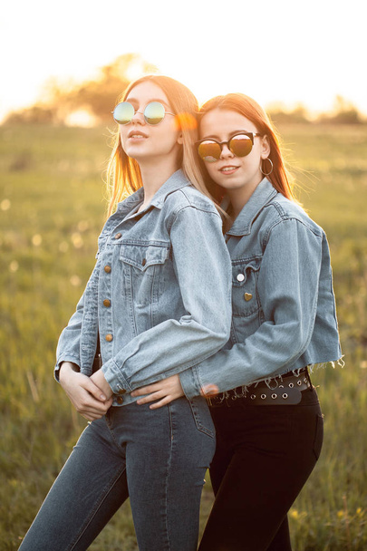 Two young women standing together outdoors at sunset. Best friends - Valokuva, kuva
