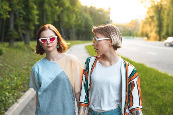 Two fashionable young women walking in the city at sunset - Foto, afbeelding