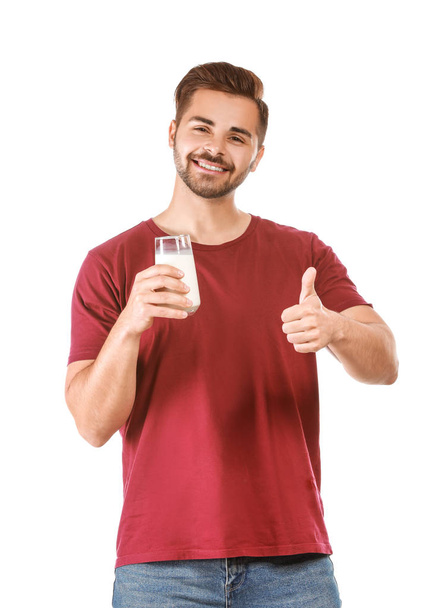Handsome man with glass of tasty milk showing thumb-up gesture on white background - Foto, immagini