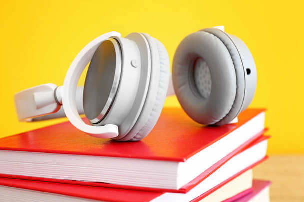 Βιβλία και μοντέρνα ακουστικά στο τραπέζι, κοντινά πλάνα. Έννοια του ηχοβιβλίου - Φωτογραφία, εικόνα