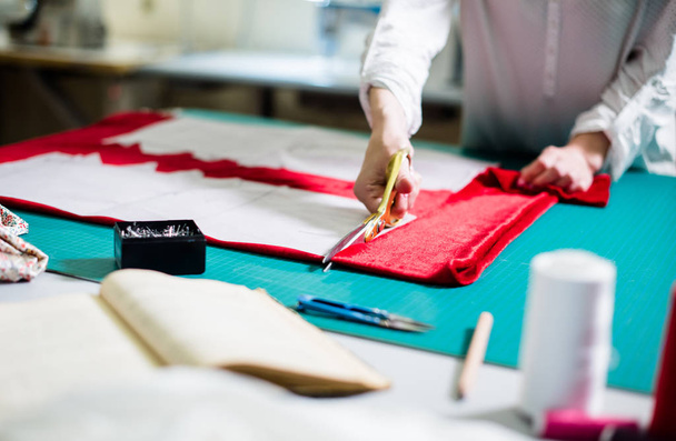 Ruce Lady Krejčí pracují ve svém studiu, nástrojích a vzorcích textilií na šicí tabulce - Fotografie, Obrázek