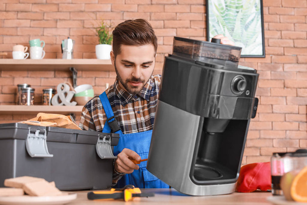 Mann repariert Kaffeemaschine in Küche - Foto, Bild
