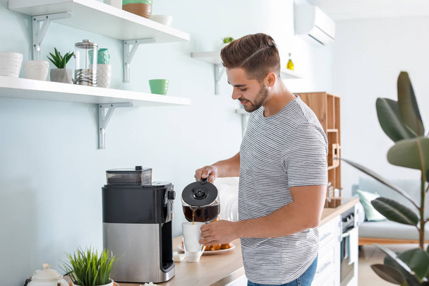 Όμορφος άνθρωπος χρησιμοποιεί καφετιέρα στην κουζίνα - Φωτογραφία, εικόνα