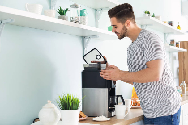 Красивый человек с помощью кофеварки на кухне
 - Фото, изображение
