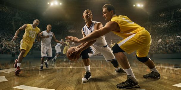 Παίκτες μπάσκετ σε μεγάλο επαγγελματικό γήπεδο κατά τη διάρκεια του παιχνιδιού. Οι αρσενικοί παίκτες του μπάσκετ παλεύουν για την μπάλα - Φωτογραφία, εικόνα