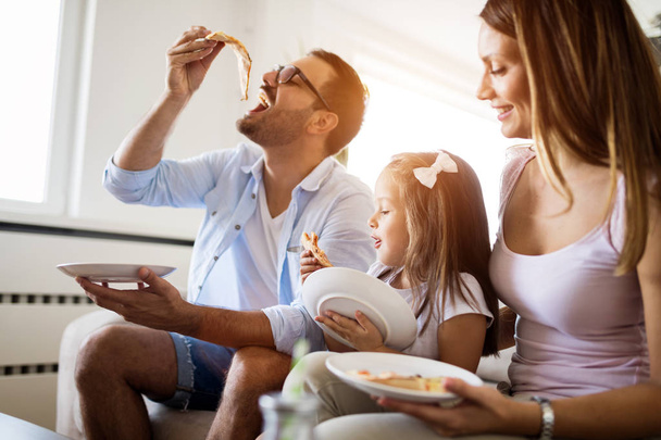 Retrato de familia feliz compartiendo pizza juntos en casa
 - Foto, imagen