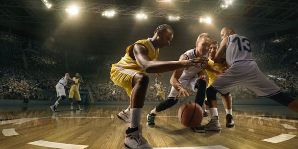 Koszykarze na dużej profesjonalnej arenie podczas gry. Mężczyźni koszykarze walczą o piłkę - Zdjęcie, obraz