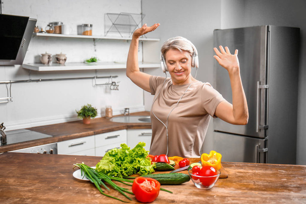 Donna matura che balla mentre cucina in cucina
 - Foto, immagini