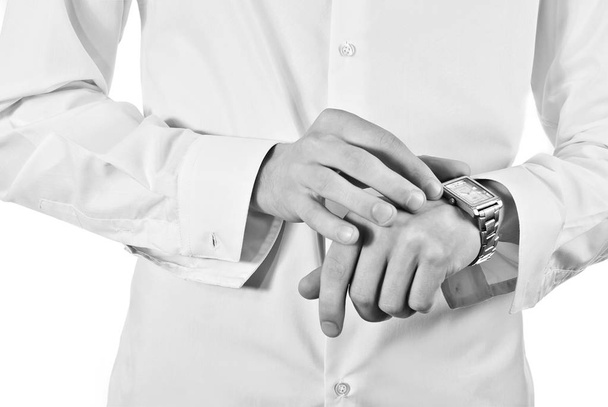 The man is preparing for an important meeting. Beginning of the wedding day. The bridegroom wears a shirt and looks at the watch. Hand with a clock isolated on a white background close up. - Foto, Imagen