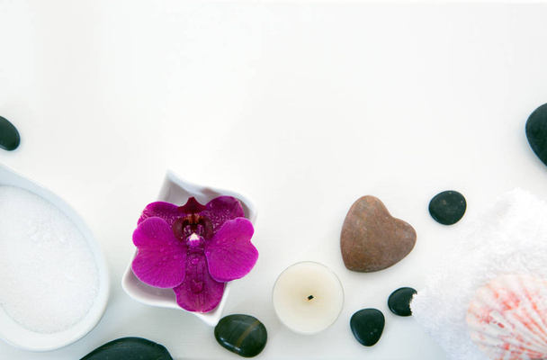 Спа-салон с розовыми орхидеями, черными камнями и солями для ванн на фоне дерева. - Фото, изображение