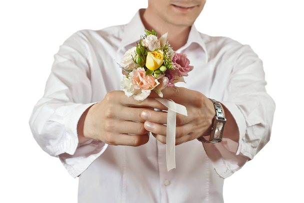 Bouquet of flowers in a man's hand. Little wedding bouquet on a white background. A man in a white shirt gives flowers. - Photo, image