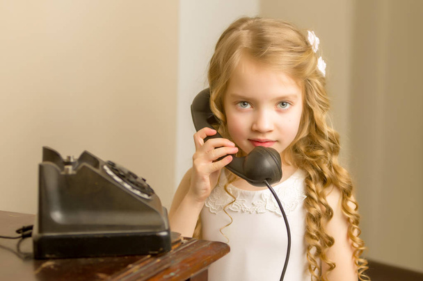 A little girl is ringing on the old phone. - Photo, image
