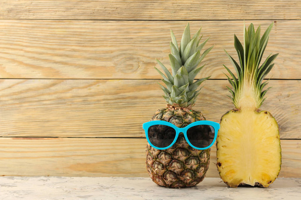 Piña de fruta madura en gafas de sol sobre un fondo de madera natural. Verano. espacio para texto
 - Foto, imagen