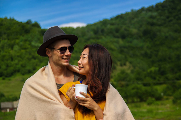 森の中の若い美しいカップルは自然を楽しみ、お茶を飲む. - 写真・画像