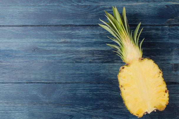 Verse rijpe ananas helften op blauwe houten achtergrond. Zomer. Vruchten. bovenaanzicht. ruimte voor tekst - Foto, afbeelding