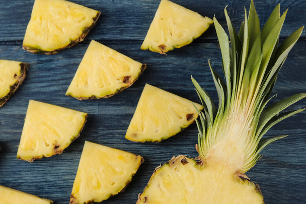 Fresh ripe pineapple halves and pineapple slices on blue wooden background. summer. fruits. top view. - Φωτογραφία, εικόνα