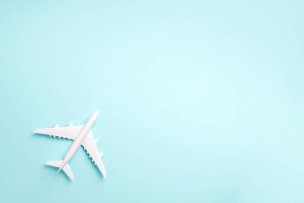 ホワイトプレーン、コピースペースと青のパステルカラーの背景に飛行機。トップビュー、フラットレイアウト。ミニマルなデザイン。旅行、休暇のコンセプト - 写真・画像