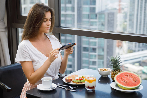 Young and happy woman taking picture of her delicious breakfast - Foto, Imagen