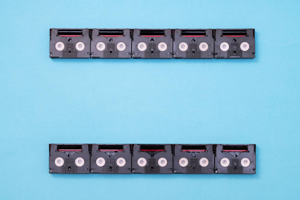 Koncept analogové filmové obrazovky vyrobený z Mini DV kazetových kazet, které se používají pro natáčení za den. Vzor vyrobený z plastových videopásek na modrém pozadí - Fotografie, Obrázek