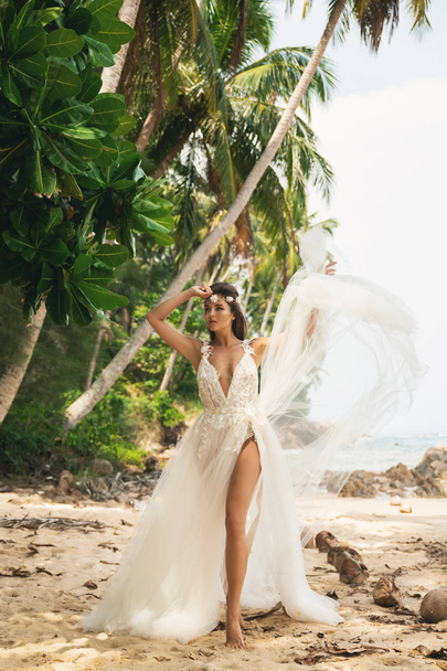 Sensual bride wearing beautiful wedding dress on the tropical is - Foto, afbeelding