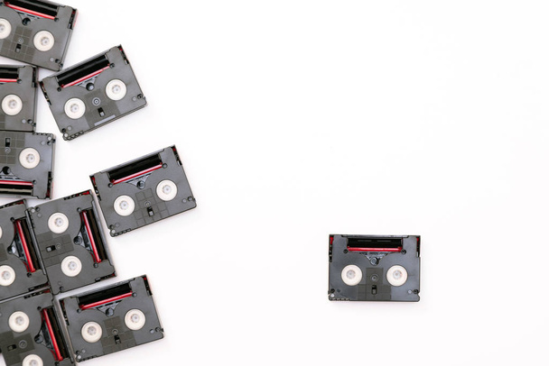 Винтажные мини-кассеты, используемые для съёмок в один день. Случайный узор из пластиковых видеолент на белом фоне
 - Фото, изображение