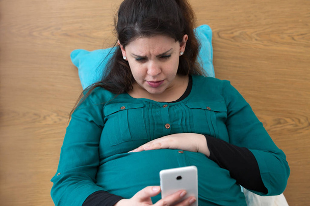 Aanstaande jonge moeder zoeken op haar Smartphone - Foto, afbeelding