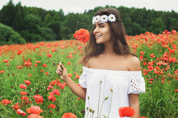 Beautiful woman in field with a lot of poppy flowers - Фото, изображение