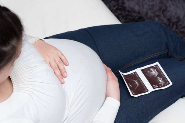 Werdende Mutter schaut auf den Ultraschall ihres Kindes - Foto, Bild