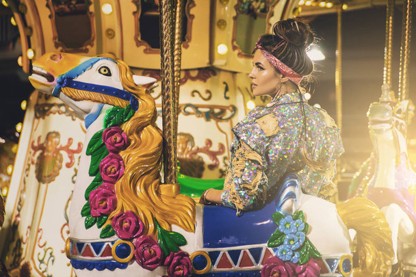 Stylish woman wearing sparkling jacket on the carousel - Zdjęcie, obraz