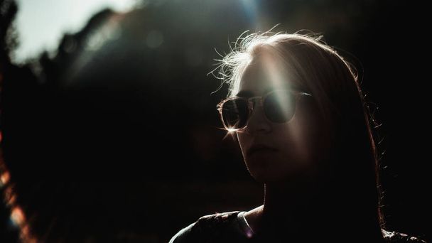 日光の下でスタイリッシュなサングラスを持つ若い女性の肖像画  - 写真・画像