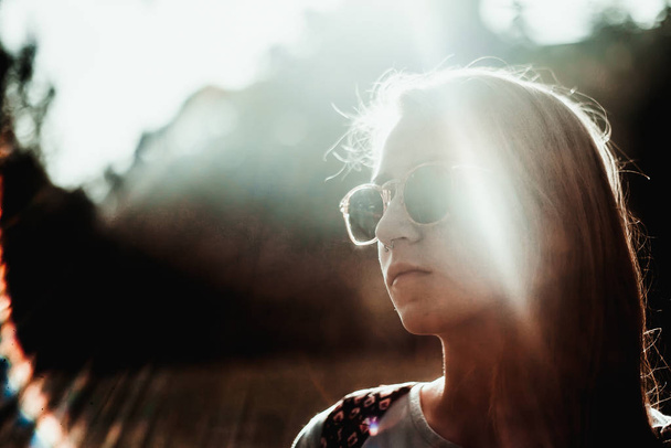 Portrait of young woman with stylish sunglasses in sunlight  - 写真・画像