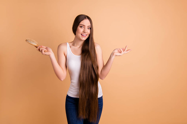 Close up photo beautiful her she lady arms hands hair brush presenting very long brown hair great condition curls result use wear casual white tank-top jeans denim isolated pastel beige background - Fotoğraf, Görsel