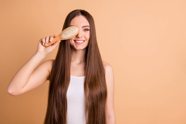 Portrait of her she nice-looking attractive lovely well-groomed cheerful cheery lady holding in hand comb closing face smooth soft silky hair effect keratin isolated on beige pastel background - Foto, afbeelding