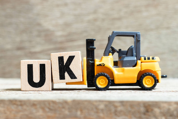 Toy wózek trzymać blok literowy k, aby zakończyć słowo UK (skrót od zjednoczonego królestwa) na tle drewna - Zdjęcie, obraz