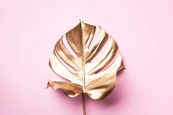 Golden tropical monstera leaf on pink background with copy space. Top view. Flat lay. Creative layout. Exotic summer concept in minimal style - Fotó, kép