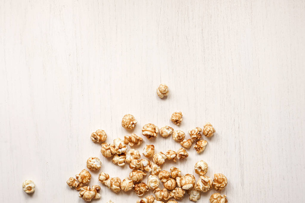 Caramelized popcorn on a white wooden background. Caramel popcor - Fotó, kép