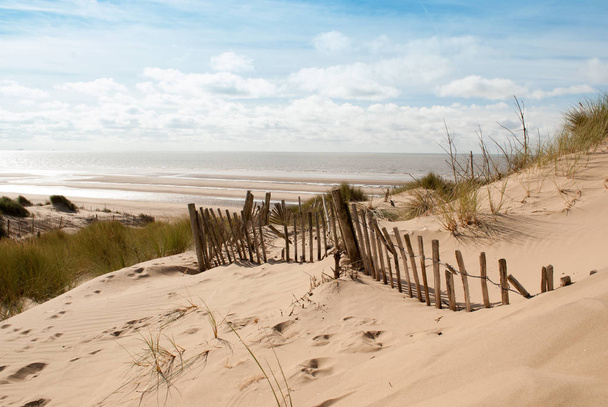 морське зображення моря, вид зверху піщаної дюни зі старим зламаним парканом, що біжить вниз
 - Фото, зображення