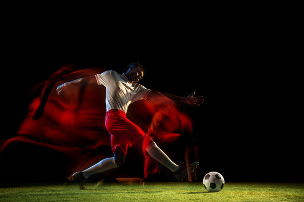 Férfi focista rúgás labdát a sötét háttér vegyes fényben - Fotó, kép