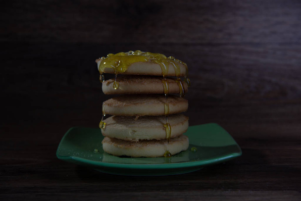 Cinq biscuits ronds se dressent les uns sur les autres sur une soucoupe verte, le miel sucré verse sur les biscuits
. - Photo, image