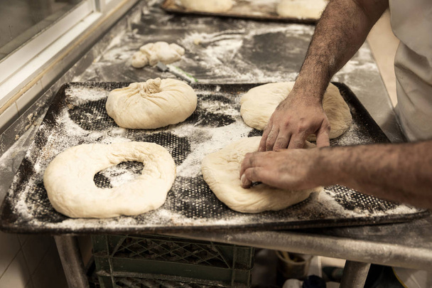 hands of the master baker in bread production - Photo, Image
