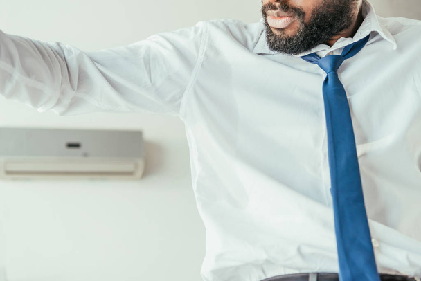rajattu näkymä afrikkalainen amerikkalainen liikemies katselee hikinen paita kärsiessään lämpöä
 - Valokuva, kuva