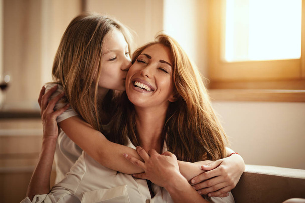 Happy smiling young mother spending time with daughter on bed at home - Φωτογραφία, εικόνα