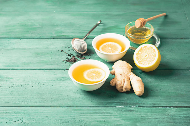 Té limón jengibre con miel en una taza blanca sobre un fondo rústico de madera. Bebida saludable para la salud de desintoxicación
. - Foto, imagen