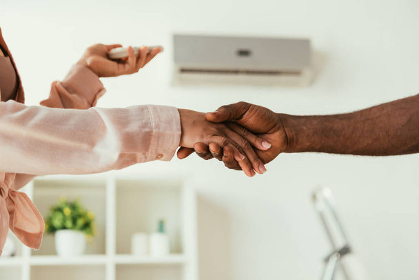 cropped view of african american woman and handyman shaking hands - Photo, Image
